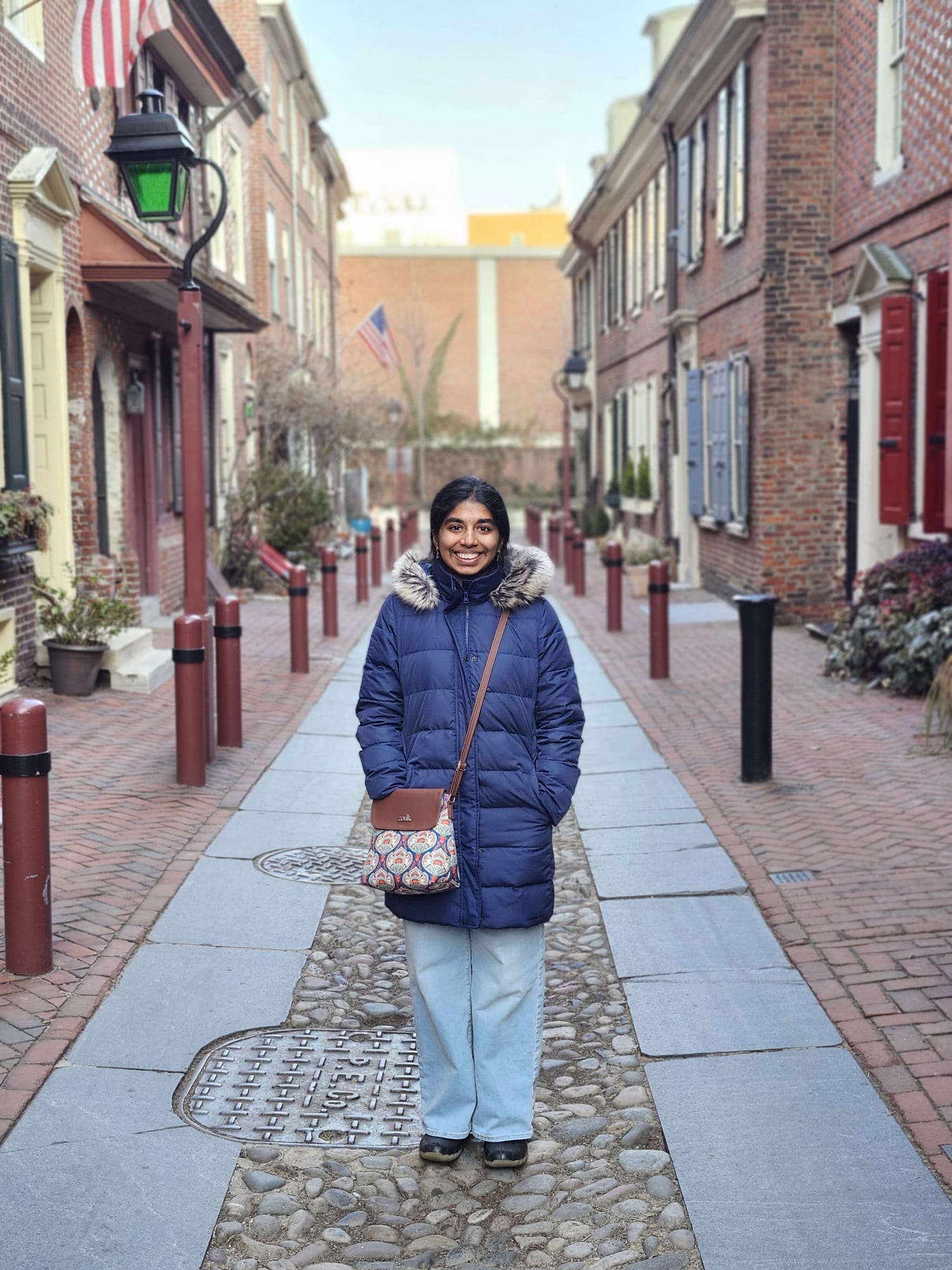 Woman outside in long blue coat, smiling, on a sunny day